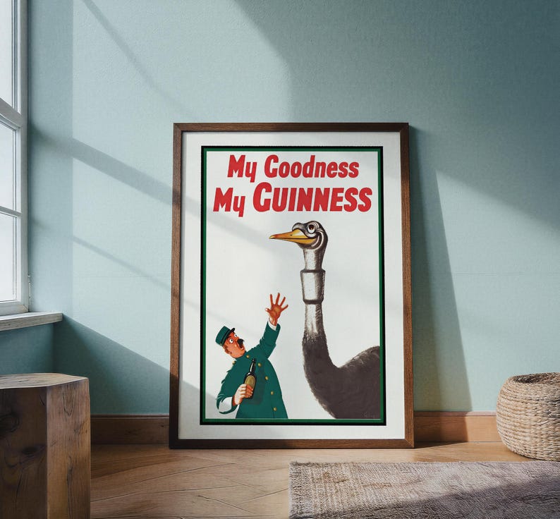 May include: Framed vintage Guinness advertisement featuring a cartoon ostrich with a long neck and a man in a green uniform. The text "My Goodness My Guinness" is in red and white. The artwork is in a wooden frame.