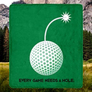 May include: Green blanket with a white golf ball design, a curved white line, and a starburst. The text "EVERY GAME NEEDS A HOLE" is printed in black at the bottom. The background shows a mountain and trees.