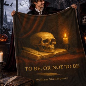May include: A rectangular throw blanket featuring a dark, atmospheric print of a human skull resting on an open book next to a lit candle. The text "TO BE, OR NOT TO BE" and "William Shakespeare" is printed in gold lettering on the lower section.