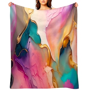 May include: A colorful blanket with an abstract design. The blanket features a blend of pink, purple, teal, and gold hues, creating a flowing, watercolor-like effect. The design is displayed on a soft, flowing fabric.