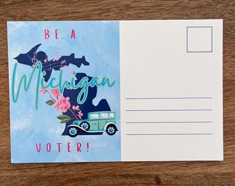 May include: A postcard with a blue and white watercolour design featuring the state of Michigan. The text reads "BE A Michigan VOTER!" with a vintage car and floral accents. The postcard has a blank back with a stamp box.
