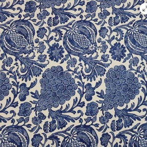 May include: A fabric featuring a repeating pattern of blue floral and botanical designs on a cream background. The pattern includes stylized flowers, leaves, and other organic shapes, creating a classic, elegant look. Suitable for various home decor projects.