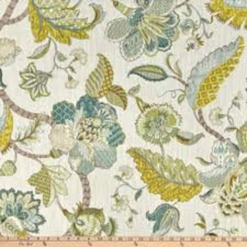 May include: Floral fabric with a white background and a large-scale pattern of blue, green, and yellow flowers. The fabric has a subtle texture.