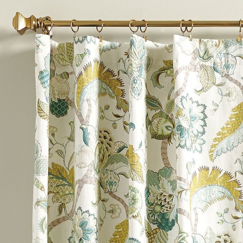 May include: White curtains with a floral pattern in shades of green, blue, and yellow. The curtains have a gold rod and rings.