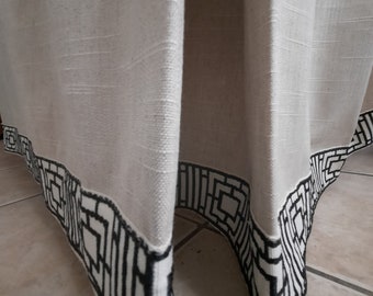May include: Close-up of the bottom edge of a pair of white linen curtains with a black geometric pattern trim.