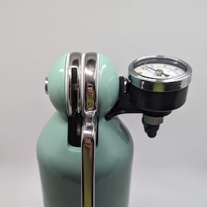 Pode incluir: Um sif&atilde;o de soda verde menta com uma pega cromada e um man&oacute;metro. O man&oacute;metro tem um mostrador preto com marcas brancas e uma agulha prateada.