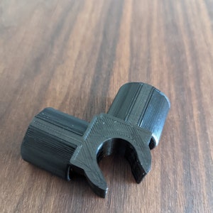 May include: Black plastic 3D printed corner bracket with a clip on one side.