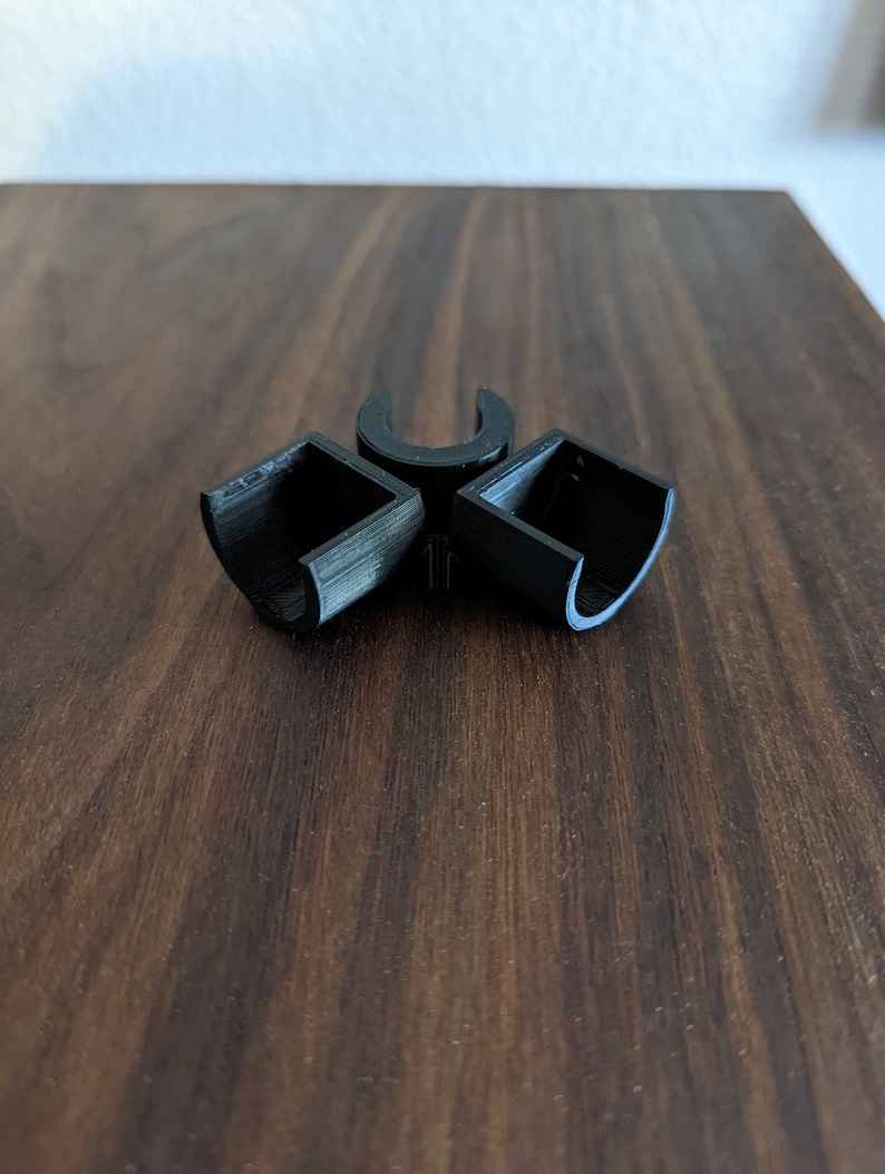 May include: Three black plastic connectors for joining pipes or tubing. The connectors are shaped like a 'U' and have a square opening on each side.