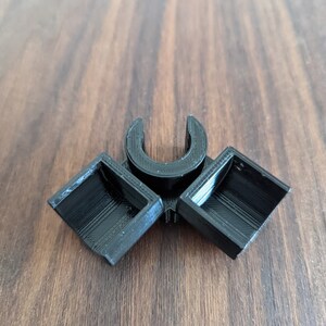 May include: A black plastic 3D printed connector with two square openings and a U-shaped opening in the center.
