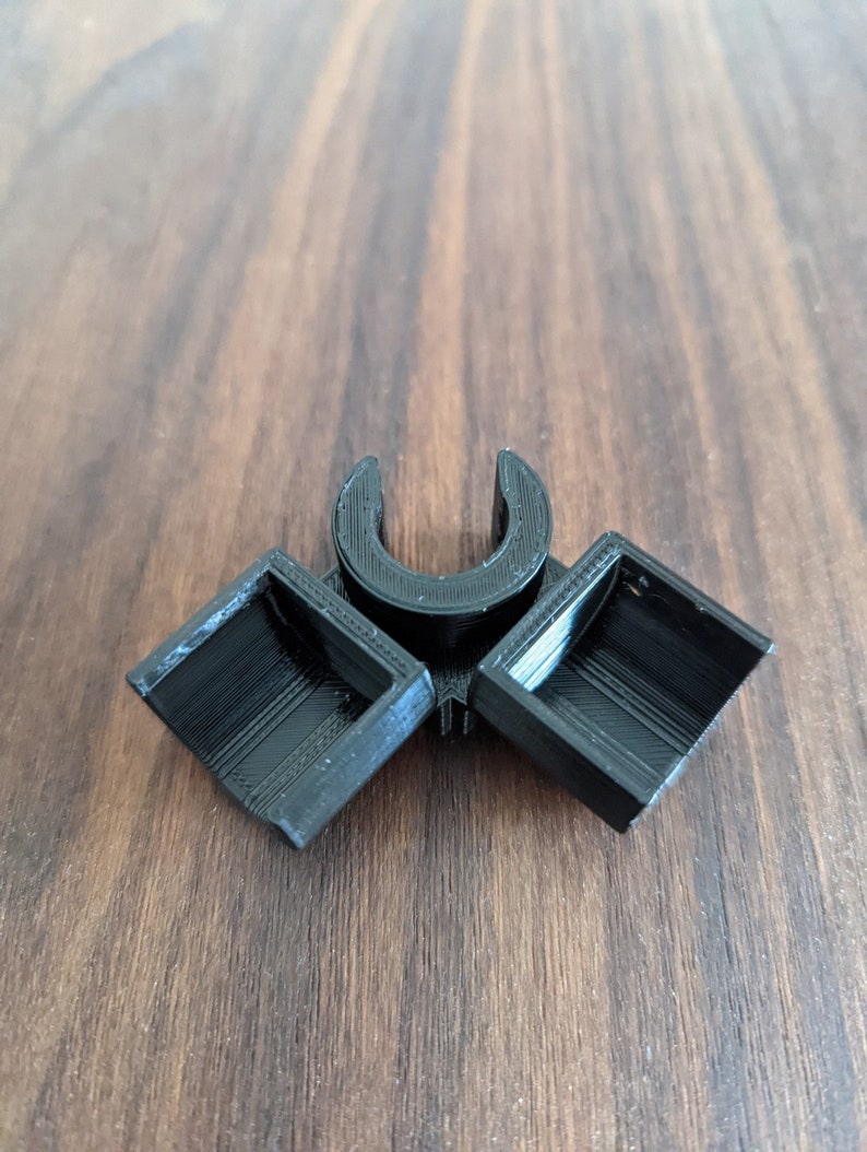 May include: A black plastic 3D printed connector with two square openings and a U-shaped opening in the center.