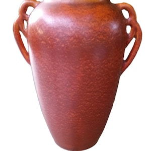 May include: A terracotta-colored ceramic vase with a mottled, textured finish. The vessel features a rounded body that tapers toward the base and a wide opening at the top. Two symmetrical, open-loop handles are attached to the upper sides.