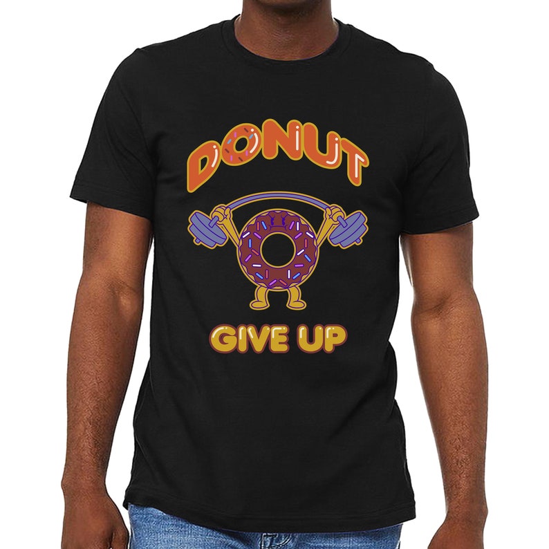 Może przedstawiać: Czarny T-shirt z kresk&oacute;wkowym pączkiem podnoszącym ciężary. Pączek ma brązową polewę i kolorowe posypki. Tekst "DONUT GIVE UP" jest nadrukowany na koszulce na pomarańczowo.