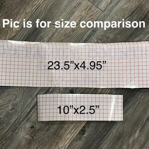 May include: Two pieces of material with a red grid pattern, one measuring 23.5" x 4.95" and the other 10" x 2.5". The text "Pic is for size comparison" is at the top. The items are on a wood-grain surface.