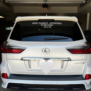 May include: White Lexus LX 570 SUV with a black bumper and red taillights. A white decal on the rear window reads "GOD, FAMILY, COUNTRY. In that order. - Charlie Kirk."