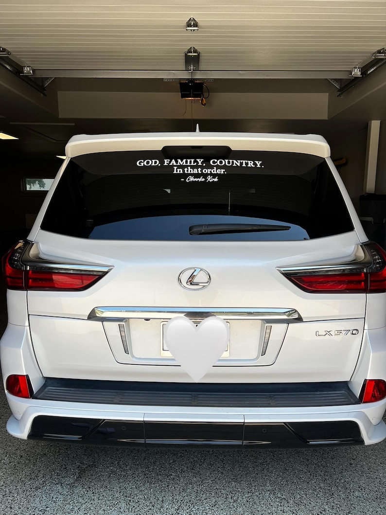 May include: White Lexus LX 570 SUV with a black bumper and red taillights. A white decal on the rear window reads "GOD, FAMILY, COUNTRY. In that order. - Charlie Kirk."