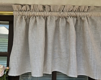 Puede incluir: Una cenefa de rayas marrones y blancas con un borde superior fruncido. La cenefa está hecha de una tela ligera y está colgada en una ventana con un marco marrón.