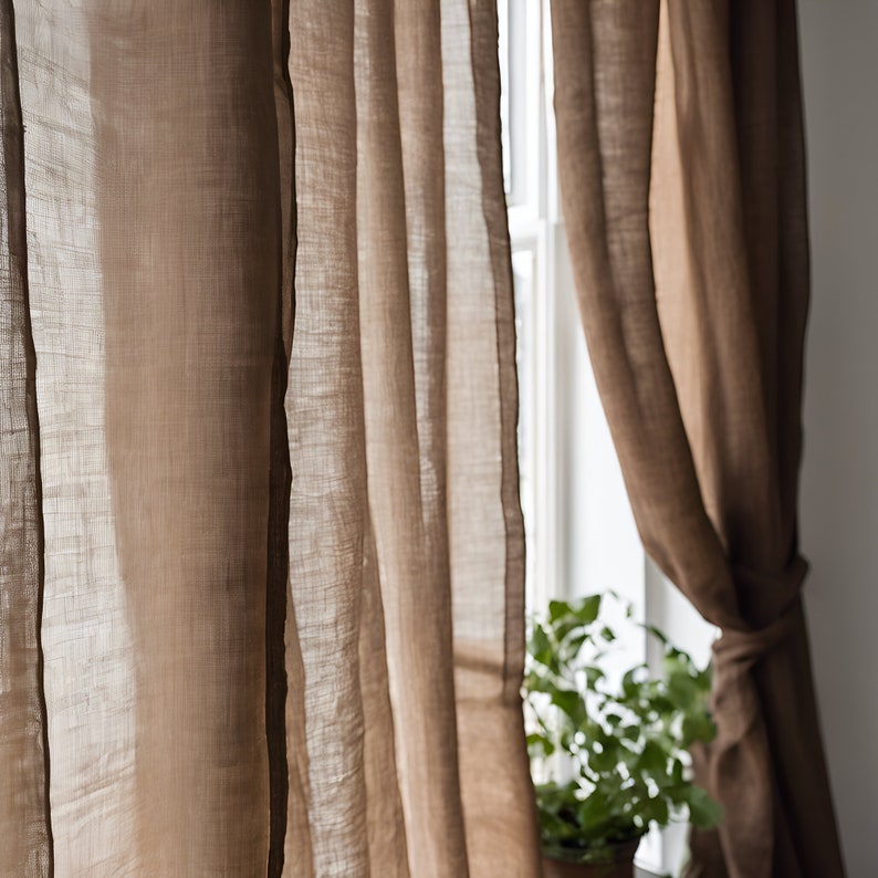 K&ouml;nnte beinhalten: Zwei braune Leinenvorh&auml;nge h&auml;ngen an einem Fenster und lassen sanftes Licht durch den Stoff scheinen.