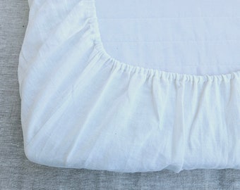 May include: White fitted sheet with a gathered elastic edge. The sheet is made of a soft, natural fabric.