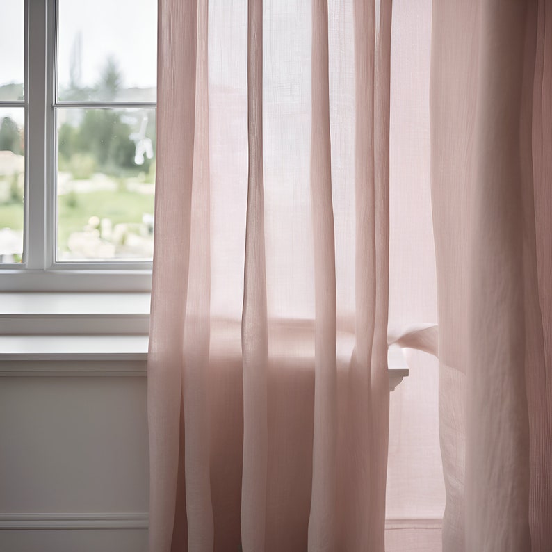 K&ouml;nnte beinhalten: Zwei durchsichtige rosa Vorh&auml;nge h&auml;ngen an einem Fenster und lassen Licht durch den Stoff scheinen.