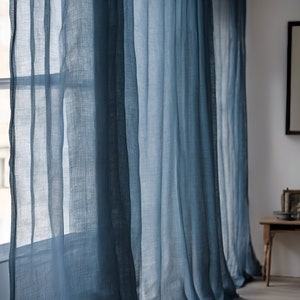 Può includere: Tende blu trasparenti appese a una finestra, con la luce che filtra attraverso il tessuto.