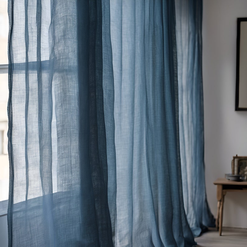 K&ouml;nnte beinhalten: Blaue, durchsichtige Vorh&auml;nge h&auml;ngen an einem Fenster, durch die das Licht scheint.