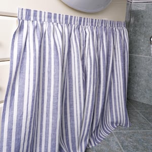 Puede incluir: Una cenefa de tela a rayas blancas y azules con un borde superior fruncido. La cenefa está hecha de una mezcla de lino y es perfecta para agregar un toque de estilo farmhouse a cualquier baño.