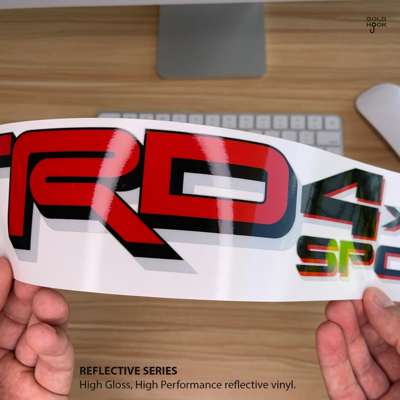May include: Reflective decal sticker with the words "TRD" in red, "4" in black, and "SPORT" in green and black. The sticker is on a white background and has a high gloss finish. The text "REFLECTIVE SERIES" and "High Gloss, High Performance reflective vinyl." is printed below the sticker.
