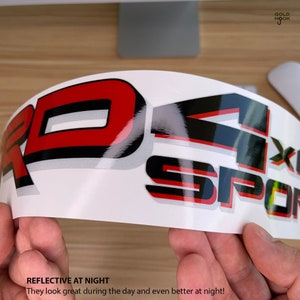 May include: A close-up of a red and black reflective decal with the text "4x4 Sport" and the words "Reflective at Night" and "They look great during the day and even better at night!" printed below.