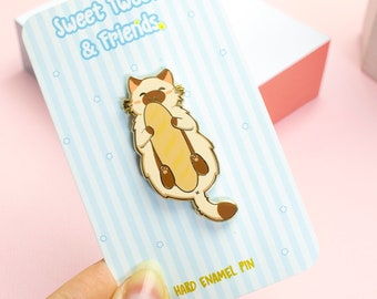 May include: Gold enamel pin featuring a cartoon cat holding a baguette. The pin is on a blue and white striped card with the text "Sweet Tweets & Friends" and "Hard Enamel Pin".