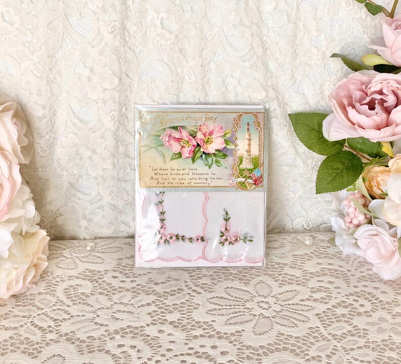 May include: Two white handkerchiefs with embroidered pink flowers and a vintage card with a pink floral design and the text "Decoration Day. Let them be quiet here, Where birds and blossoms be, And tell to you who bring the tear, And the rose of memory."