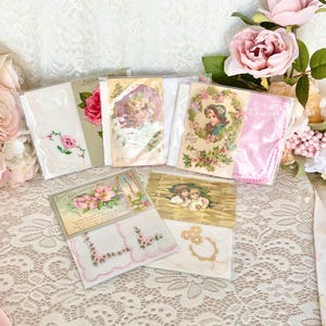 May include: A collection of vintage handkerchiefs and postcards with floral and lace designs. The handkerchiefs are white with pink embroidery and the postcards feature images of children and flowers.