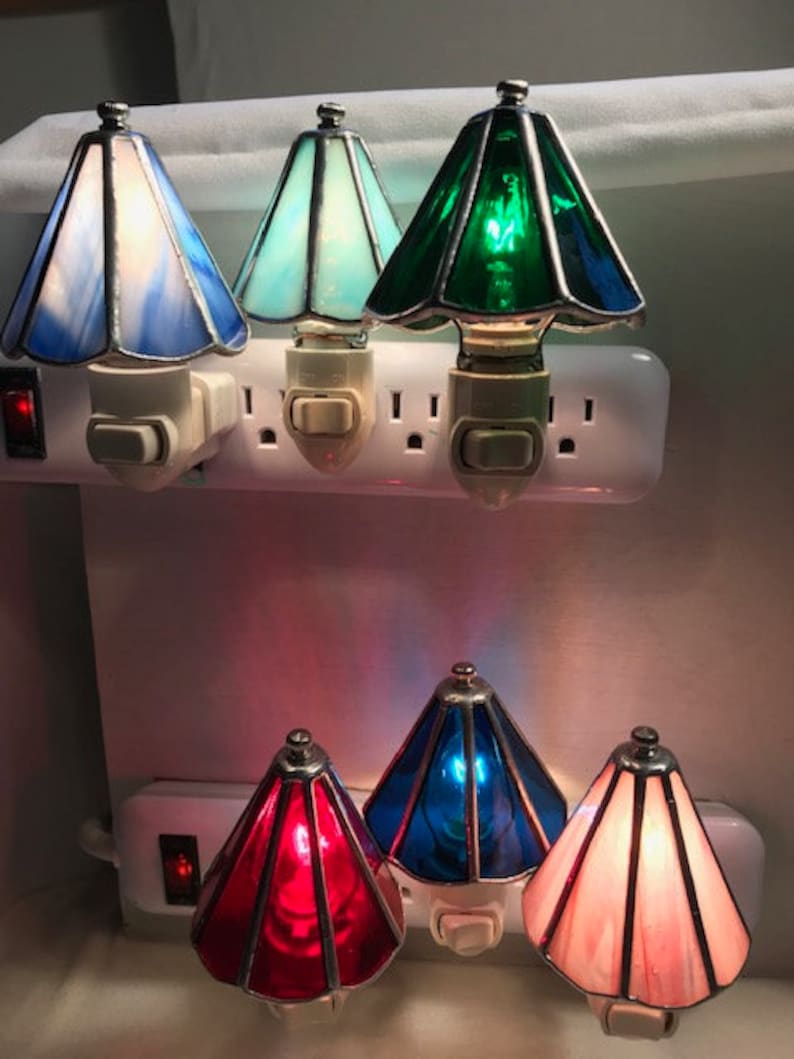 Picture of six lamp shade night lights plugged into outlets. They are blue, light blue, green, red, dark blue, and pink.