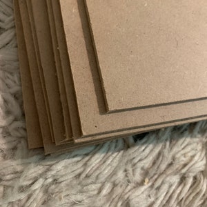 May include: A stack of brown cardboard sheets, likely for crafting or DIY projects.