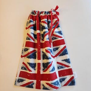 May include: A drawstring bag featuring the Union Jack flag design in red, white, and blue. The bag has a red ribbon drawstring closure at the top. The fabric has a slightly distressed look.