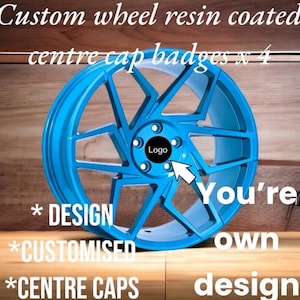 以下が含まれることがあります： ユニークなスポークデザインの、カスタムライトブルーホイール。 センターキャップには黒いロゴがあります。 画像のテキストは「Custom wheel resin coated centre cap badges x 4」、「Design」、「Customised」、「Centre Caps」、「You're own design」です。