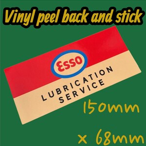 以下が含まれることがあります： 赤とベージュの背景を持つ長方形のビニールステッカー。 エッソのロゴが左上にあります。 テキスト「LUBRICATION SERVICE」は黒で印刷されています。 ステッカーのサイズは150mm x 68mmです。