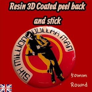 Op de afbeelding: Een ronde knoop van 50 mm met een rood en geel ontwerp met de tekst "HIS MILLION DOLLAR MAN" en een illustratie van een man. De knoop heeft de tekst "Resin 3D Coated peel back and stick".