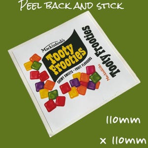 May include: A white sticker with a black and yellow logo for Tooty Frooties chewy sweets. The logo features the text "Tooty Frooties" and "Mackintosh's". The sticker is decorated with colorful candy squares and the text "Chewy Sweets - Fruit Flavours". The sticker is 110mm x 110mm.