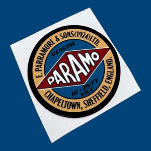 May include: A vintage sticker with a circular design featuring the text "F. Parramore & Sons (1924) Ltd. Genuine Param Hi-Duty Vice, Chapelton, Sheffield, England." The logo has red, blue, and gold accents on a white background.