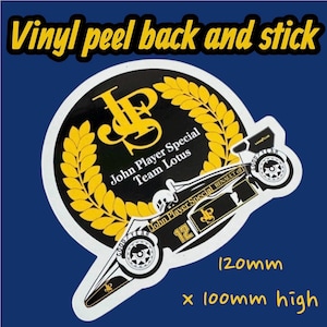 May include: A vinyl peel-and-stick sticker featuring a black and gold logo with the text "John Player Special Team Lotus." The sticker also includes a race car design and measures 4.7 inches wide by 3.9 inches high.