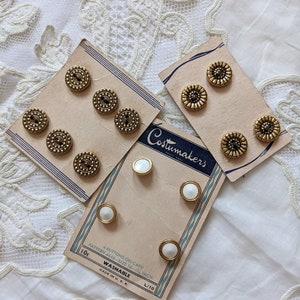 Könnte beinhalten: Vier Karten mit Knöpfen, zwei Karten mit weißen Knöpfen und zwei Karten mit goldenen Knöpfen. Die Karten sind mit "Costumakers" beschriftet und tragen den Text "4 Knöpfe auf Karte, Muster 4446, Größe 18 - (Zoll), 10c, waschbar, hergestellt in den USA, L/10".