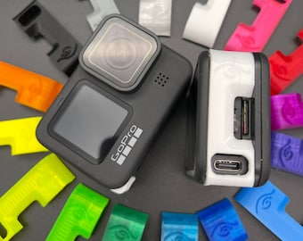 May include: A black GoPro Hero 10 camera with a white case and a variety of colorful plastic accessories. The accessories are small and have a unique design.