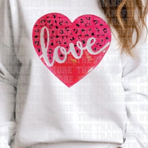 May include: White sweatshirt with a pink heart-shaped sequin patch that says "love" in black script.