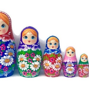 May include: A set of eight traditional Russian nesting dolls, also known as matryoshka dolls. The dolls are painted with colorful floral patterns and feature smiling faces. The largest doll is blue with red, white, and pink flowers. The dolls decrease in size, with the smallest doll being a miniature version of the largest.