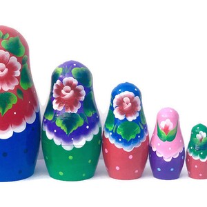 May include: A set of six nesting dolls, also known as Russian nesting dolls, with colorful floral designs. The dolls are painted in shades of blue, red, green, pink, and purple. The largest doll is blue with red and white flowers, the second largest is green with purple and white flowers, the third largest is red with blue and white flowers, the fourth largest is purple with pink and white flowers, the fifth largest is red with white flowers, and the smallest is blue with white flowers.