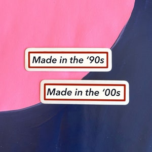 May include: Two white rectangular stickers with red borders. The top sticker says "Made in the '90s". The bottom sticker says "Made in the '00s".