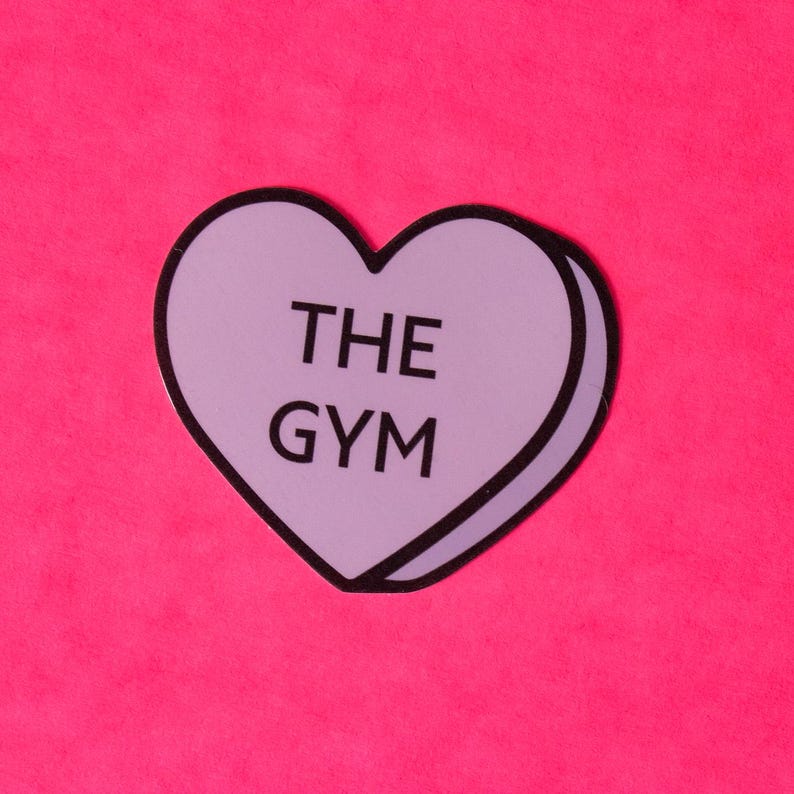 Może przedstawiać: Fioletowa naklejka w kształcie serca z tekstem "THE GYM" na r&oacute;żowym tle.