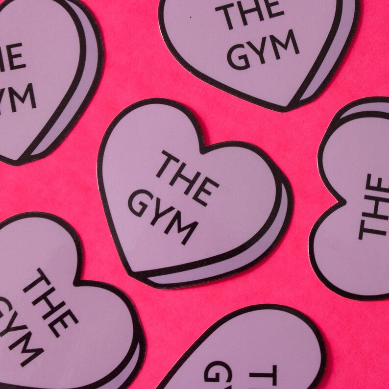 Może przedstawiać: Sześć fioletowych naklejek w kształcie serca z czarnymi obramowaniami i tekstem "THE GYM" na każdej.