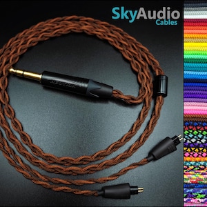 Puede incluir: Cable de audio trenzado marrón con conector jack dorado y conectores negros. El cable está etiquetado como "NEUTRIK" y está enrollado sobre una superficie oscura. La imagen también muestra una carta de colores de cables disponibles. El texto "SkyAudio Cables" está en la esquina superior derecha.