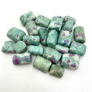 May include: A collection of tumbled stones, primarily green with red and white inclusions. The stones vary in size and shape, with rounded edges. The overall appearance is natural and earthy, suggesting a focus on gemstones or crystals.
